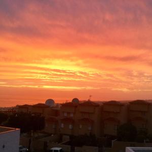 una puesta de sol sobre una ciudad con un edificio en primer plano en Windsor Panoramic Las Americas, en Adeje