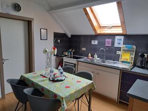 Magnifique petit appartement tout équipé, silencieux في Anhée: مطبخ مع طاولة وكراسي ومغسلة