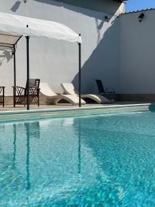 a swimming pool with chairs and an umbrella at Villa Ramadia in Floridia