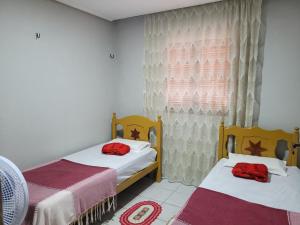 a bedroom with two beds and a window at Aluguel Temporada em Martins/RN in Martins