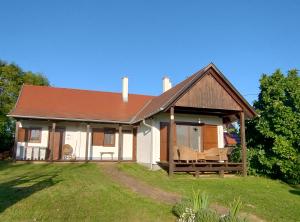 a white house with a brown roof and a yard at Őrségi Porta in Magyarszombatfa