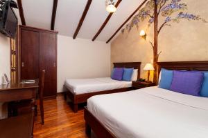 a hotel room with two beds and a desk and a tv at Hotel Casa San Rafael in Cuenca