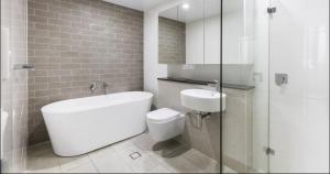 a white bathroom with a toilet and a sink at Comfortable Living - NO PARTIES- 3 Bedroom sleeps 6, parking, pool, other amenities - Near Showgrounds in Sydney