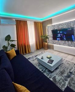 sala de estar con sofá azul y TV de pantalla plana en Cazare Ploiesti, en Ploieşti