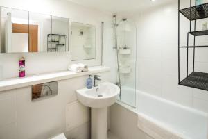 La salle de bains blanche est pourvue d'un lavabo et d'un miroir. dans l'établissement Cozy 1 bedroom / Gloucester Road / Kensington, à Londres