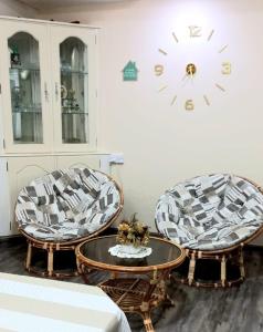 2 chaises et une table dans une pièce avec une horloge dans l'établissement Appartment Camellia, à Flic-en-Flac