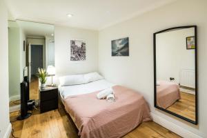 - une chambre avec un lit et un grand miroir dans l'établissement Cozy 1 bedroom / Gloucester Road / Kensington, à Londres