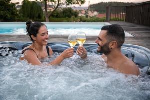 a man and woman holding champagne glasses in a hot tub at Casa do Sear - Turismo Rural & Spa Exterior in Sanxenxo
