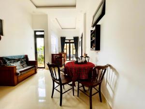 uma sala de jantar com uma mesa e cadeiras e um sofá em Mini Home em Ấp Ða Lợi