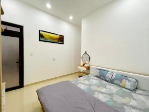 Ấp Ða LợiにあるMini Homeのベッドルーム1室(ベッド1台付)が備わります。壁に絵が飾られています。