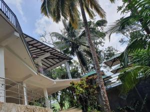 a house with a staircase and palm trees at Singheraja Lodge in Deniyaya