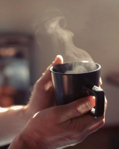 una persona sosteniendo una taza negra con humo saliendo en Finca del Sacramento, en Colonia del Sacramento