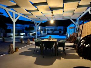 a patio with a table and chairs under a pergola at Family Villages Santorini in Vlychada Beach