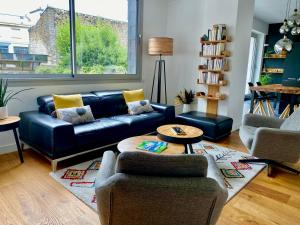uma sala de estar com um sofá de couro preto e cadeiras em Les Briochines - Cocon cosy en plein centre-ville em Saint-Brieuc