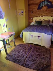 a bedroom with a bed and a table and a rug at Au jardin du lac in Gaussan