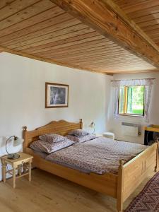 sypialnia z drewnianym łóżkiem i drewnianym sufitem w obiekcie Chalupa Slunečná w mieście Želnava