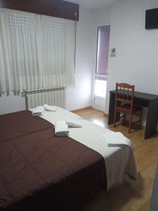 a bedroom with a bed and a desk and a chair at Pension KM66 in Palas de Rei