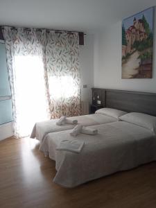 1 dormitorio con 2 camas y ventana en Pension KM66, en Palas de Rei 