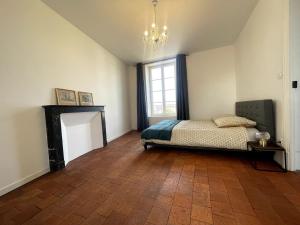 1 dormitorio con cama, chimenea y lámpara de araña en Gite les Minimes II, en Avallon