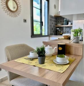 - une table en bois avec des tasses et des soucoupes dans la cuisine dans l'établissement Le Coeur DAISY'L Saint Denis Centre, à Saint-Denis