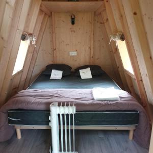 1 dormitorio en una cabaña de madera con 1 cama. en Camping Pyrénées Nature, en Oloron-Sainte-Marie