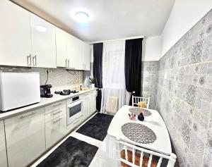 a kitchen with white cabinets and a table in it at Cazare Ploiesti in Ploieşti