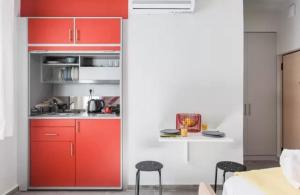 アテネにあるColorful apartment in Athensの赤いキャビネットと黒いスツール付きのキッチン