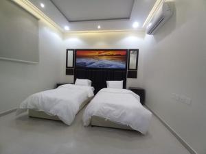 dwa łóżka w pokoju z obrazem na ścianie w obiekcie شقق مفروشة - توافيق w mieście Burajda
