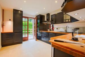 a kitchen with black cabinets and a wooden counter top at Villa Paséo - Swimming pool and large garden - Near Deauville and Trouville in Bonneville-sur-Touques