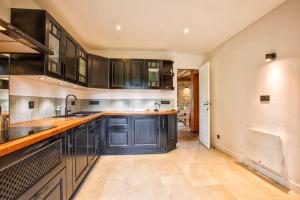 a kitchen with black cabinets and wooden counter tops at Villa Paséo - Swimming pool and large garden - Near Deauville and Trouville in Bonneville-sur-Touques