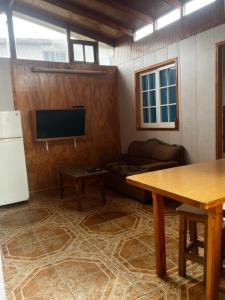 a living room with a couch and a tv and a table at Cabañas San Joaquin in Isla Negra