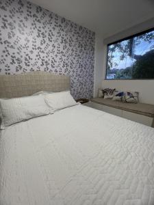 una camera da letto con un grande letto bianco e una finestra di Village Ninho da Jandaia a Mata de Sao Joao