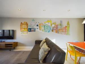 a living room with a couch and a wall with drawings at Donegall Sq Apt at City Gate, Belfast City Centre in Belfast