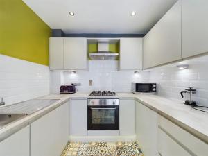a kitchen with white cabinets and a stove top oven at Donegall Sq Apt at City Gate, Belfast City Centre in Belfast