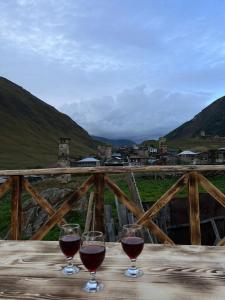twee glazen rode wijn zittend op een houten tafel bij Guest House Buba in Ushguli
