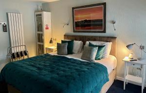 a bedroom with a large bed with a green blanket at Lochindaal Hotel in Port Charlotte