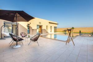 une terrasse avec des chaises et un parasol ainsi qu'une piscine dans l'établissement Villa Kassia , Jacuzzi, Hamman, jeux…, à Marrakech