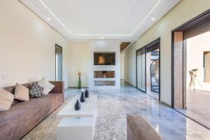 een woonkamer met een bank en een tv bij Villa Kassia , Jacuzzi, Hamman, jeux… in Marrakesh