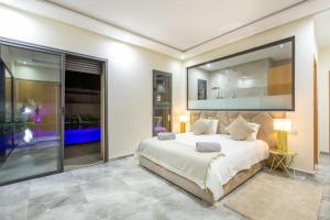 une chambre avec un grand lit et un grand miroir dans l'établissement Villa Kassia , Jacuzzi, Hamman, jeux…, à Marrakech 54 autres photos