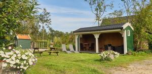 un cobertizo verde con una mesa y sillas en un patio en Noord-Hollands Hof Dream, en Spijkerboor