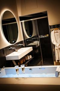 La salle de bains est pourvue d'un lavabo et de 2 verres à vin. dans l'établissement Hédoné Suite de luxe et Spa privatif, à Nancy
