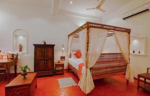 a bedroom with a bed and a dresser in a room at Marari Beach Bungalow in Mararikulam