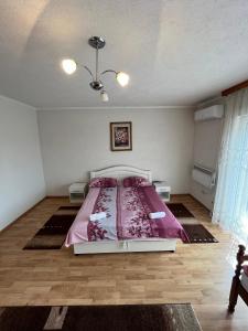 ein Schlafzimmer mit einem Bett mit einer rosa Decke in der Unterkunft Apartmani Hadžić in Živinice