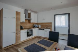 uma cozinha com armários brancos e uma mesa com cadeiras em Landhaus ANDREA em Litzelsdorf