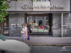 Daiwa Roynet Hotel Kyoto Shijo Karasuma في كيوتو: سيدتان واقفتان أمام مبنى