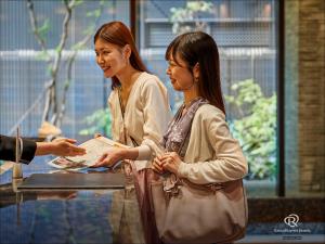 京都市にあるダイワロイネットホテル京都四条烏丸の二人の女性がテーブルの横に立っている