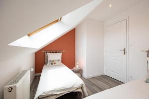 a small attic bedroom with a white bed and orange walls at Duplex Petit-Fort - proche plage in Gravelines