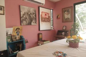 Cette chambre est dotée d'un mur rose et d'un lit. dans l'établissement Casa de campo y arte en Zona Arqueológica Ake, con alberca., à Aké