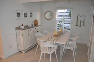 jadalnia ze stołem i białymi krzesłami w obiekcie Stunning Beach House in Grotto Bay w mieście Grotto Bay