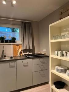 eine Küche mit weißen Schränken, einem Waschbecken und einem Fenster in der Unterkunft Gemütliche Ferienwohnung, See- und Stadtnah in Schwerin